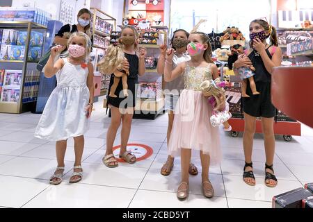 New York City, USA. 12th Aug, 2020. A group of young grils all wearing masks on a birthday party outing, watch a magic trick at the newly reopened famed toy store FAO Schwarz at Rockefeller Center in New York, NY, August 12, 2020. FAO has implemented mandatory masks for anyone entering the store, including children, social distancing floor markers and has employees continually cleaning and disinfecting surfaces when possible. (Anthony Behar/Sipa USA) Credit: Sipa USA/Alamy Live News Stock Photo