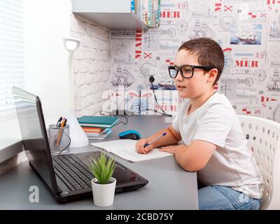 Child boy doing homework at the laptop on the online platform Stock Photo