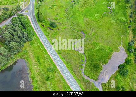 rural landscape with country road and small winding river green among meadows. aerial top view Stock Photo