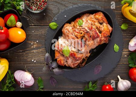 Baked pork ham on a wooden background, fried piece of meat with spices, fresh vegetables, top view Stock Photo