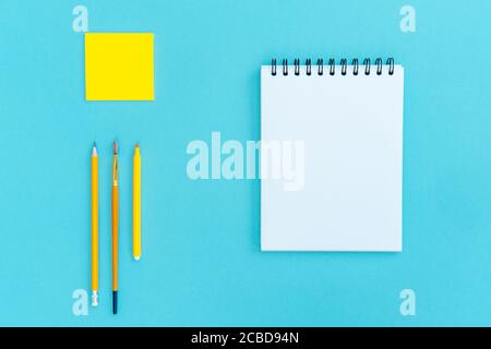Open a blank notepad on the spiral and office and school supplies on blue background. Copy space, flat lay. Back to school concept. Stock Photo