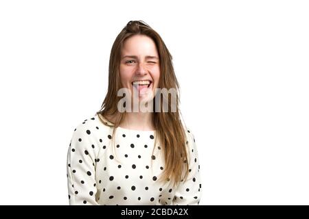 a young woman in a white polka dot dress. Sticks out his tongue. isolated in white Stock Photo