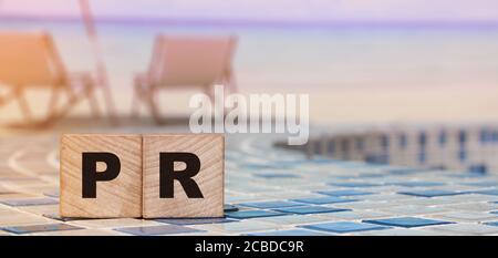 PR word on wood blocks on relaxed beach background. Luxury life business concept Stock Photo