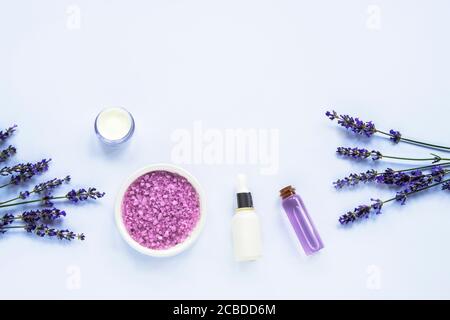 Lavender blossom, sea salt, cream jar and essential oils on white background, top view, flat lay. Stock Photo