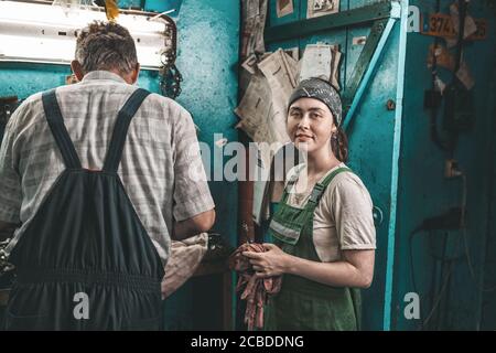 The concept of small business, feminism and women's equality. A young female apprentice stands next to a mechanic. Stock Photo