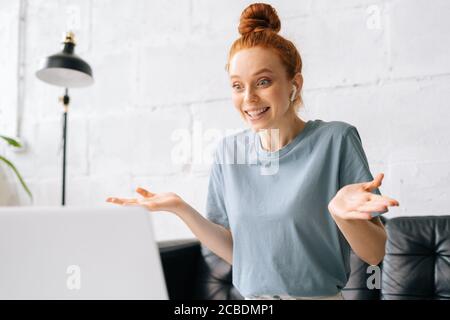 Happy surprised redhead young woman is looking at laptop screen with amazed expression Stock Photo