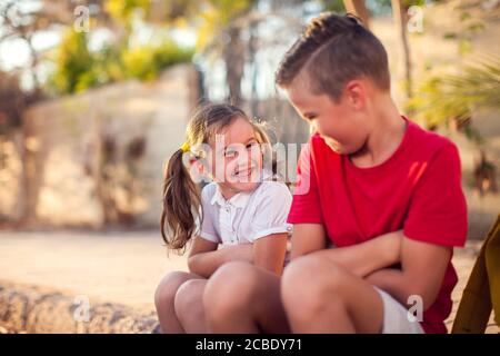Smiling pupils sitting together outdoor. Children and emotions concept. Stock Photo