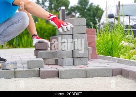 worker laying paving stones. stone pavement, construction worker laying cobblestone rocks on sand. Stock Photo