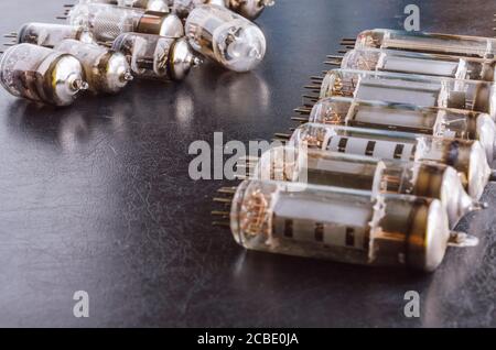 Random vacuum tubes on a black background. A group of radio tubes of different sizes and purposes. Shooting at eye level. Selective focus. Stock Photo