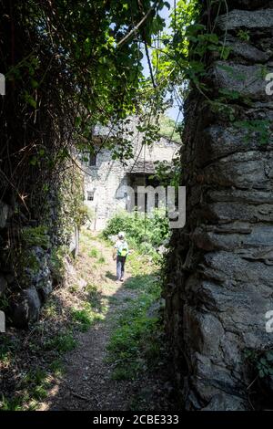 Little boy walking on path among stone huts, Costiera dei Cech, Mello, Valtellina, Sondrio province, Lombardy, Italy Stock Photo