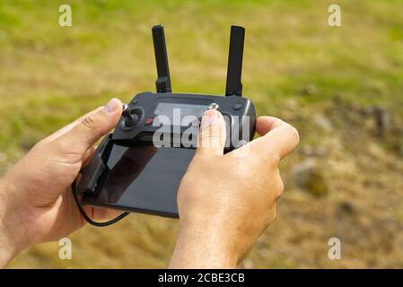 Man using remote control to operating drone assign blurred land. Stock Photo