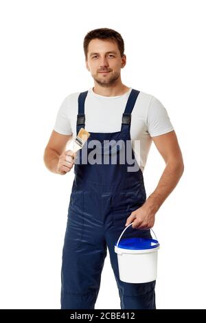 caucasian repairman in blue uniform holding paint brush and can with paint. builder or painter decorator isolated on white background Stock Photo