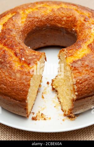 Cornmeal Cake (Bolo de Fuba) cut Brazilian style on a white plate. Isolated on jute. Front view. Close-up. Vertical shot. Stock Photo