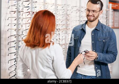 Optician giving a new pair of reading glasses to cheerful bearded patient.close up photo. job, profession, occupation