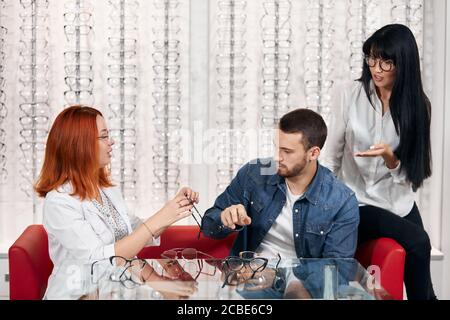 professional oculists and her colleague giving advice to a customer while sitting on the sofa. close up photo Stock Photo