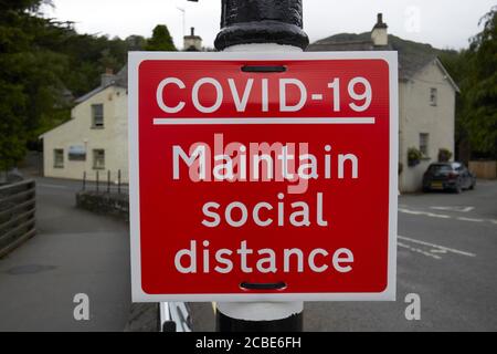 red warning sign on street for measures put in place for social distancing during the covid-19 coronavirus outbreak in the lake district cumbria engla Stock Photo