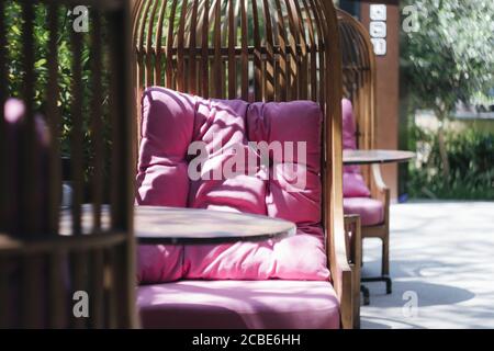 wicker chair with pink pillows on a summer veranda in a cafe Stock Photo