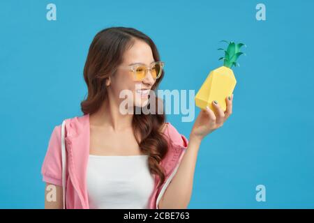 Attractive happy young woman holding fresh pineapple with a smile. Stock Photo