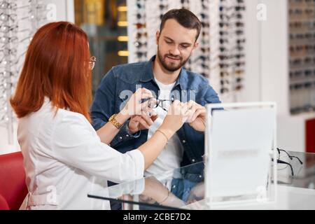 young otocian recommending a client to try on stylish glasses, fashion, job concept Stock Photo