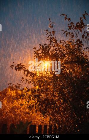 Torrential rain at night lit by a street lamp during a summer storm in the UK. Stock Photo