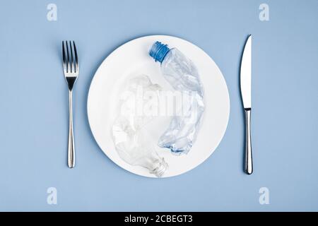 Top view of plastic waste garbage in the white plate, knife and fork Stock Photo