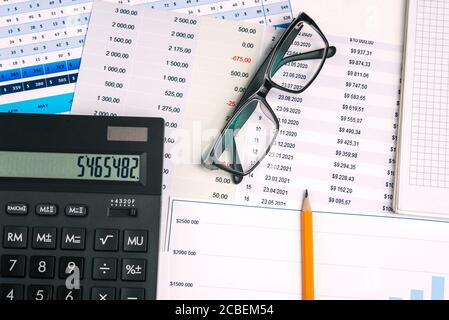 Glasses, calculator and pencil on financial documents. Analytical report and marketing research. Graph with the company's report. Business concept. Stock Photo