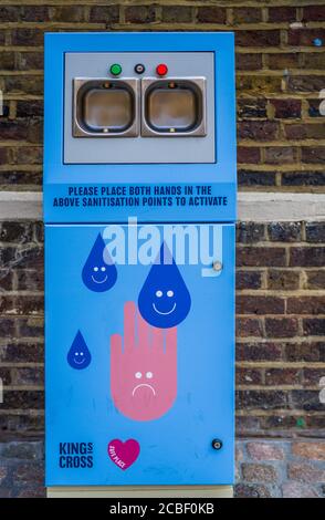 Automatic Hand Sanitiser machine at London Kings Cross - automatically sprays sanitiser when hands are inserted into the slots. Stock Photo