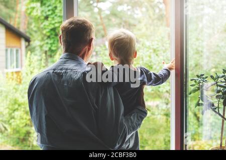 grandparenting - grandfather taking care and spending time together with grandson at home. looking through the window Stock Photo