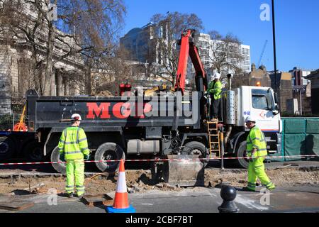 London, United Kingdom, Mar 19, 2011 : Roadworks in Tower Hill were manual workers are working as a team using a mechanical digger to make essential r Stock Photo