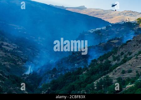 Helicopter with a water bag working to extinguish a fire in Las Alpujarras de Granada.