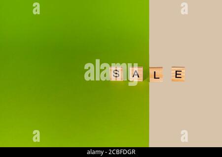 Inscription sale from wooden cubes on colored, yellow and green cardboard. Copy space. Stock Photo