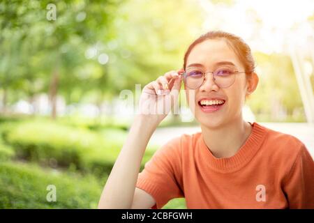 Asian woman wearing glasses happy smile with green nature outdoor background Stock Photo