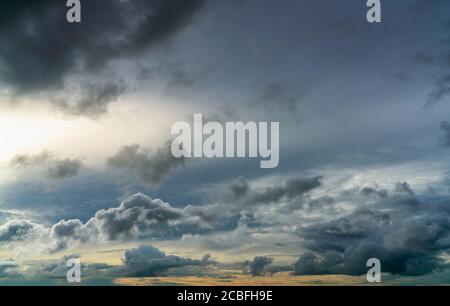 Sunset sky and gray and golden clouds. Gray sky and fluffy clouds. Thunder and storm sky. Sad and moody sky. Dead abstract background. Cloudscape. Stock Photo
