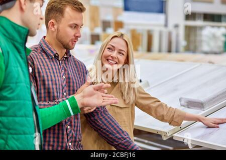 manager of distribution center or warehouse worker help cutomers with choice, married couple came to make purchase in hypermarket, they doubt buy it o Stock Photo