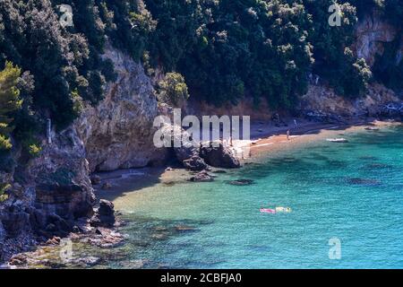 High-angle view of a bay with vacationers on a little beach at the foot of a cliff on the sea shore of the Gulf of Poets, Lerici, La Spezia, Italy Stock Photo