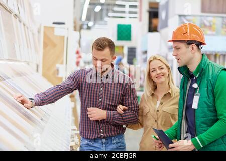 friendly warehouse worker enjoy helping customers, man in protective helmet and uniform consult, rich assortment allows him to offer a huge amount of