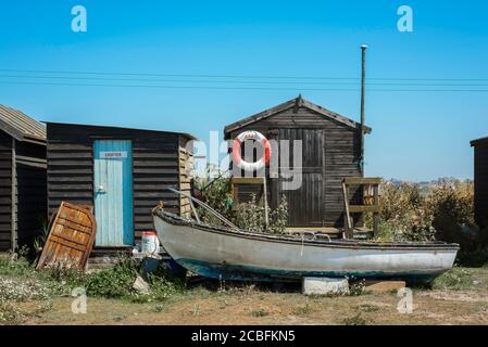 East Anglia coast, view in summer of a fishing boat and traditional fishermen's huts in Southwold harbour, Suffolk, England, UK Stock Photo