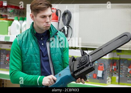 good equipment salesman try and check new commodity in store, wearing green uniform. shop, warehouse, market Stock Photo