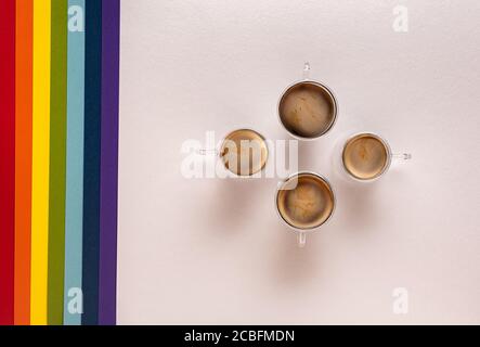 Four thermo glass cups with fresh black espresso coffee on white paper textured background with stripes of LGBT colors on side. Directly above view. C Stock Photo