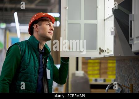 warehouse worker checking serviceability of shelves in the store. hard working staff in uniform and protective helmet Stock Photo