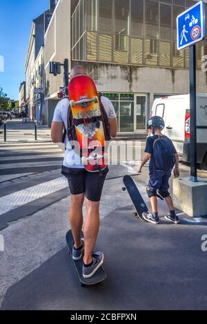 Father and son skateboarding on their way home - Nantes, Loire-Atlantique, France. Stock Photo