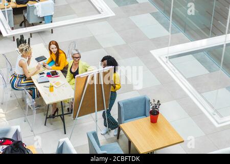 mixed race team working with whiteboard in office. top view photo. copy space.Afro businesswoman giving presentation to executive team Stock Photo