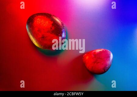 Two tumbled mineral gems colorfully illuminated showing abstract details. Stock Photo
