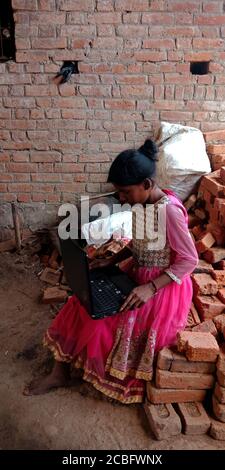 DISTRICT KATNI, INDIA - AUGUST 20, 2019: An indian village poor girl operating laptop computer, concept for asian people digital learning. Stock Photo