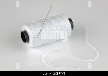white cotton reel and needle with reflection Stock Photo