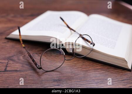 Pair of glasses with a book on wood surface Stock Photo