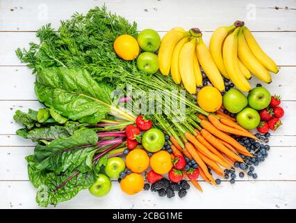 Assortment of fresh fruit and vegetables on white wooden boards. Stock Photo