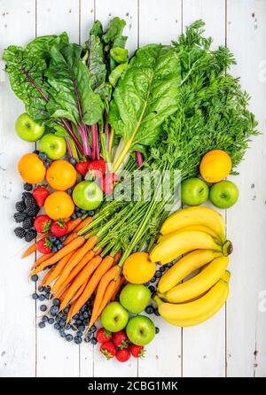 Assortment of fresh fruit and vegetables on white wooden boards. Stock Photo