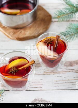 Christmas mulled red wine with spices and fruits over Christmas decorated background. Traditional hot drink made from red wine at Christmas time. Stock Photo