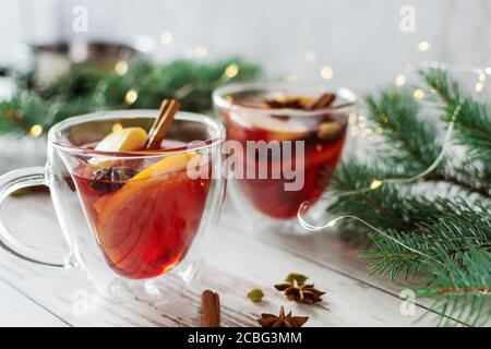 Christmas mulled red wine with spices and fruits over Christmas decorated background. Traditional hot drink made from red wine at Christmas time. Stock Photo